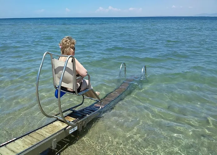 Wheelchair user on an accessible beach track descending into the Ionian sea, Corfu